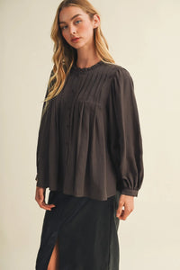A dark gray long-sleeved blouse featuring a pintuck bib ruffle collar with a pleated front design