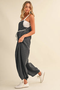 Dark gray plaid denim overalls with white straps and button closures featuring a drawcord waistline plaid design