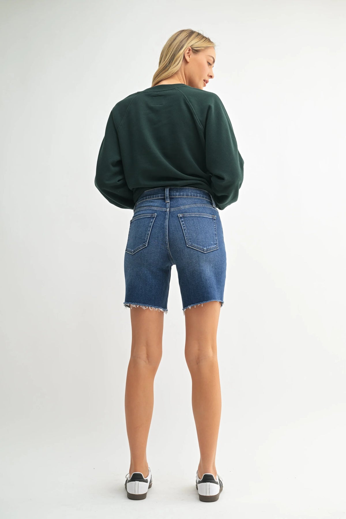 High rise scissor cut longer length denim short with dark green sweatshirt