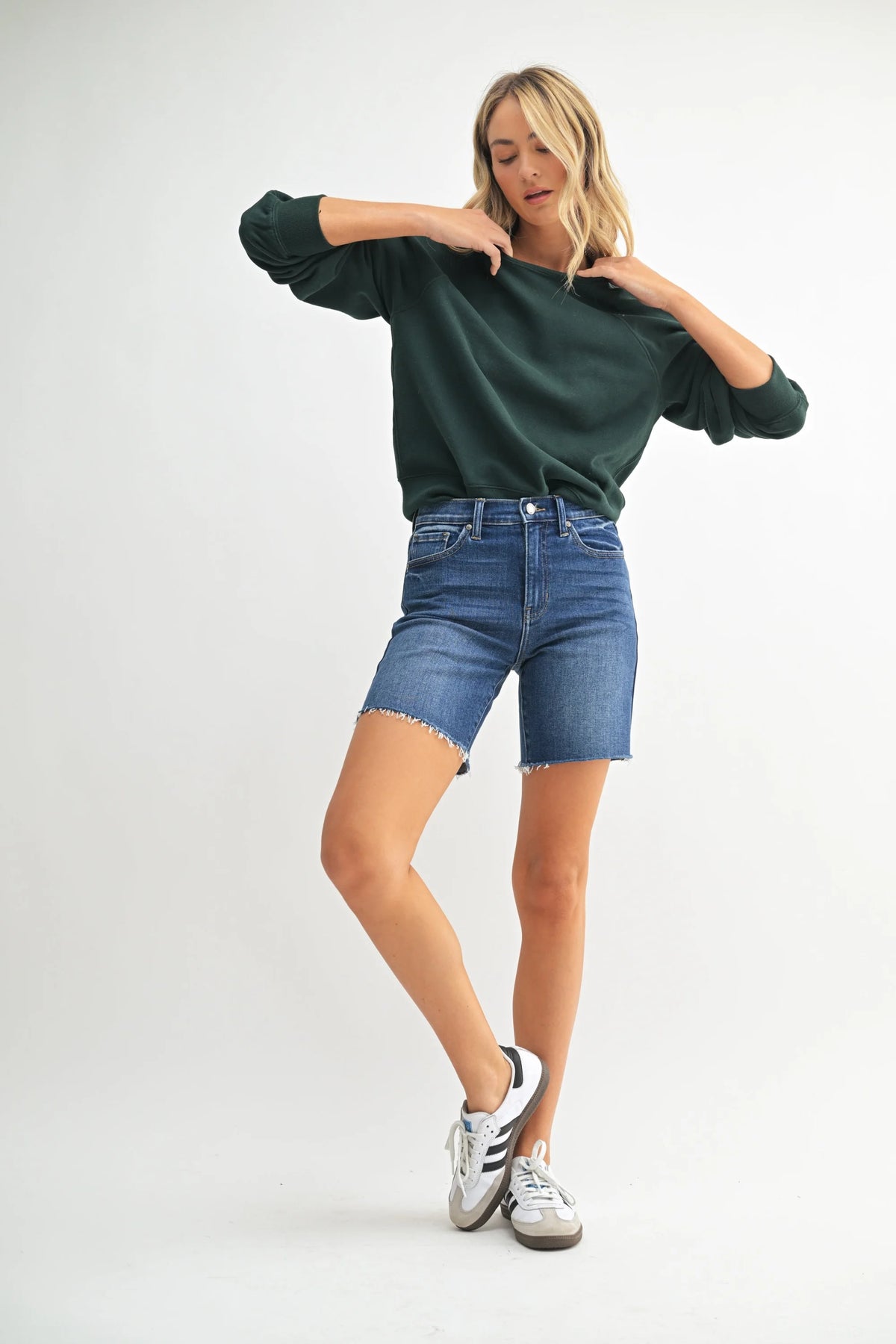 High rise scissor cut longer length denim short with dark green sweatshirt