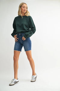 High rise scissor cut longer length denim short with dark green oversized sweatshirt