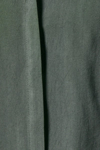 Dark green woven fabric with subtle texture and visible stitching on the collard wide shoulder button down shirt