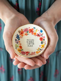 Delicate ceramic trinket bowl with vibrant floral wreath and inspiring inscription perfect for shop daisy and women’s boho chic clothing fans