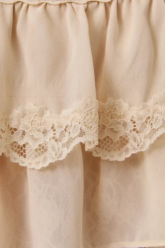 A delicate cream lace trim layered crop top with ruffled fabric and matching lace trim along the hem