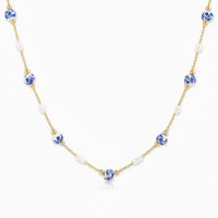 A delicate gold ceramic pearl necklace with alternating blue and white floral ceramic pearls