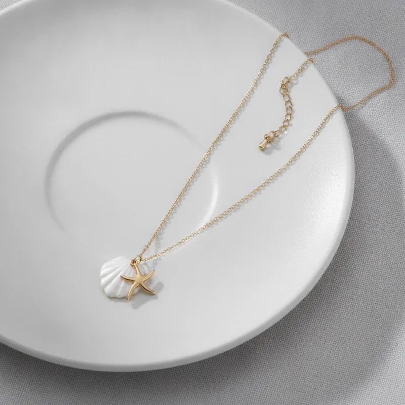 Navigational gold plated seashell and starfish charm necklace with a delicate gold chain and white shell pendant