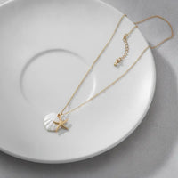 Navigational gold plated seashell and starfish charm necklace with a delicate gold chain and white shell pendant