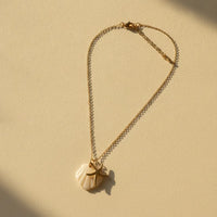 A delicate nautical gold plated necklace with a white gold plated seashell pendant and a starfish charm necklace