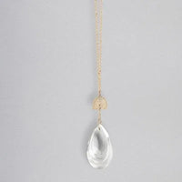 A delicate gold pocket suncatcher necklace with an intricate rainbow charm and clear crystal pendant for women’s boho chic clothing