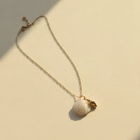 Delicate gold seashell pendant necklace with a soft white mother of pearl stone and small conch charm