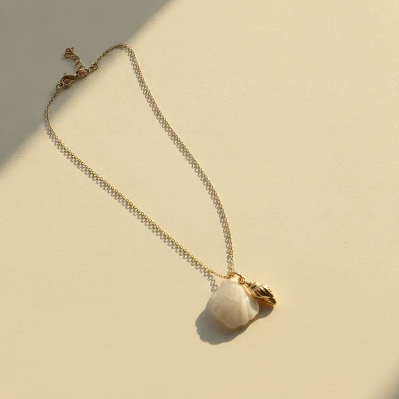 Delicate gold seashell pendant necklace with a soft white mother of pearl stone and small conch charm