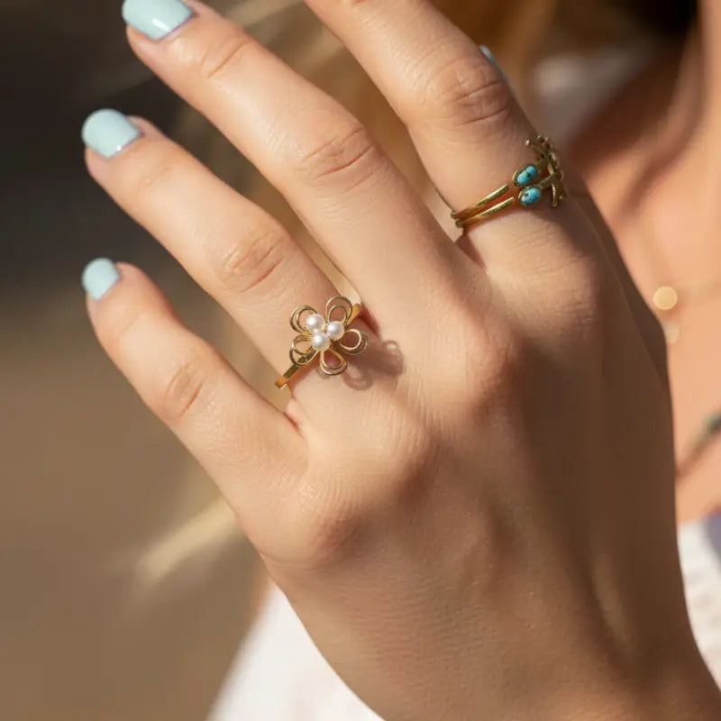 A delicate gold pearl blossom wire ring featuring a four-petal flower design with white pearl centers