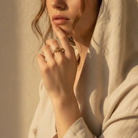 A delicate gold plated cable band statement ring with an intricate textured design adorns the woman’s finger