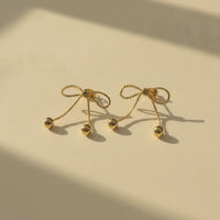 Dainty gold bow statement earrings featuring twisted rope detailing and delicate sphere tassels in gold tone