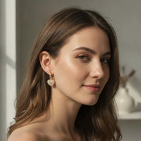 Delicate elegant gold heart hoop earrings featuring a textured heart-shaped pendant with peach crystal charm