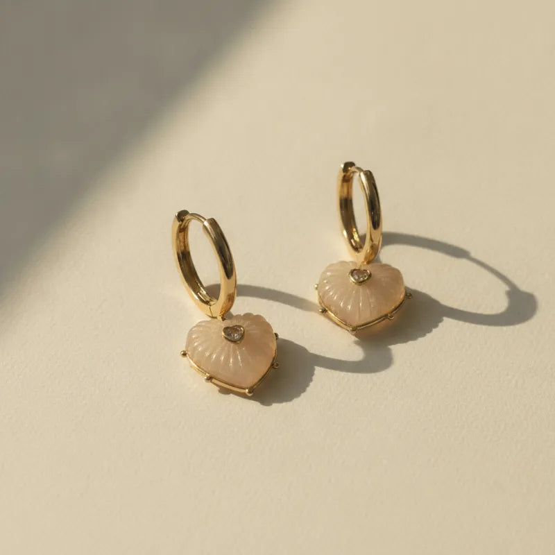 Elegant gold heart hoop earrings with blush pink resin heart pendants and clear gemstone accents