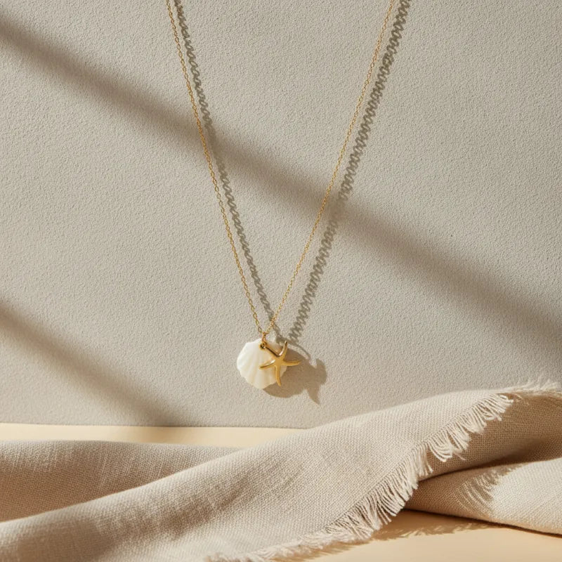 A delicate nautical gold plated necklace with a gold plated seashell pendant and starfish charm necklace on fine chains