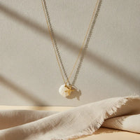 A delicate nautical gold plated necklace with a gold plated seashell pendant and starfish charm necklace on fine chains