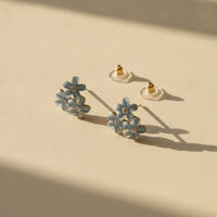 Dainty blue floral blossom stud earrings with delicate light blue enamel petals and tiny clear gemstone centers