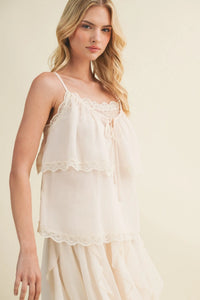 Delicate lace inset tiered off-white camisole with lace-trimmed layered design and thin spaghetti straps