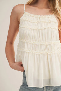 Delicate off-white tiered ruffle bodice babydoll camisole with thin spaghetti straps and soft flowing fabric