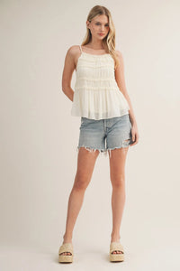 Delicate off-white tiered ruffle bodice babydoll cami with thin spaghetti straps and lightweight flowing fabric