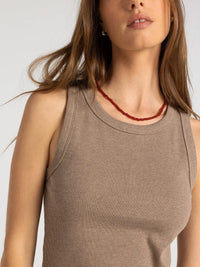 A delicate red beaded necklace worn with a white thread and supply edlin basic tank sleeveless top