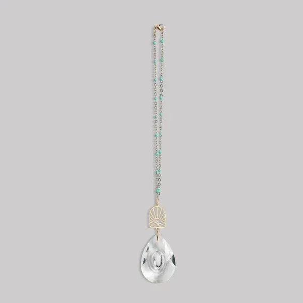 Delicate turquoise and gold pocket suncatcher necklace with clear teardrop pendant and sunburst design for women’s boho chic clothing