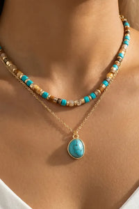 A delicate layered turquoise stone drop bead necklace with earth-toned beads and gold-tone chain featuring a turquoise pendant