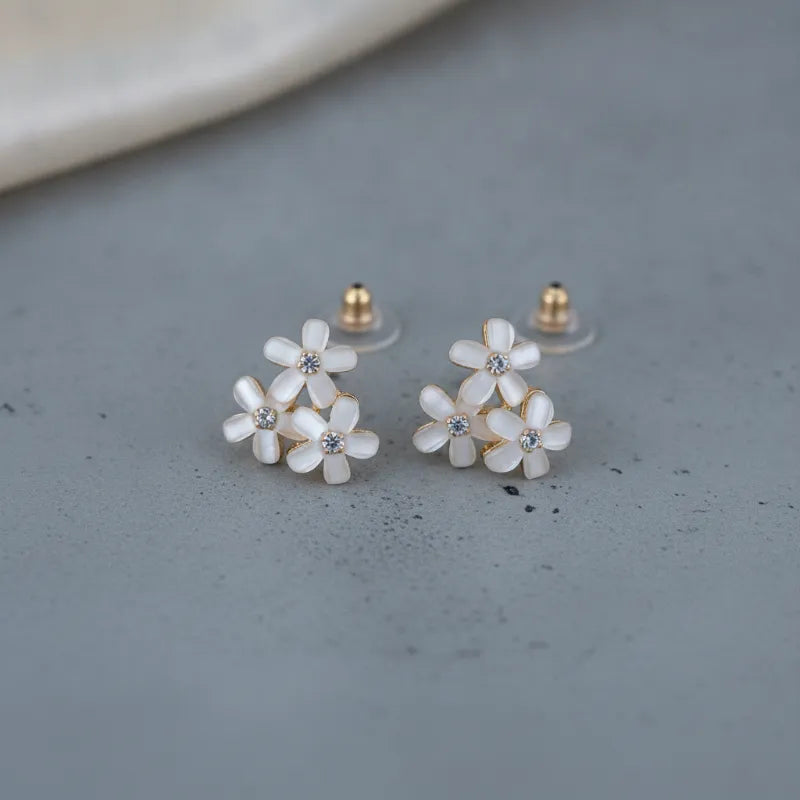 Dainty blue floral blossom stud earrings with delicate white enamel petals gold-tone settings and clear crystal centers