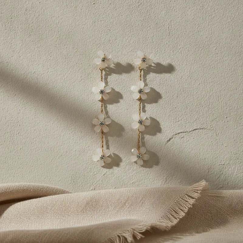 Elegant four-tier cascading white floral gold drop earrings with delicate blossoms and clear crystal centers on chains