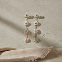 Elegant four-tier cascading white floral gold drop earrings with delicate blossoms and clear crystal centers on chains