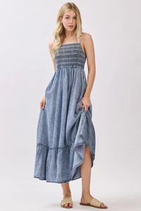 Denim blue tencel smocked tiered midi dress with sleeveless design and ruffle hem perfect for elegant occasions