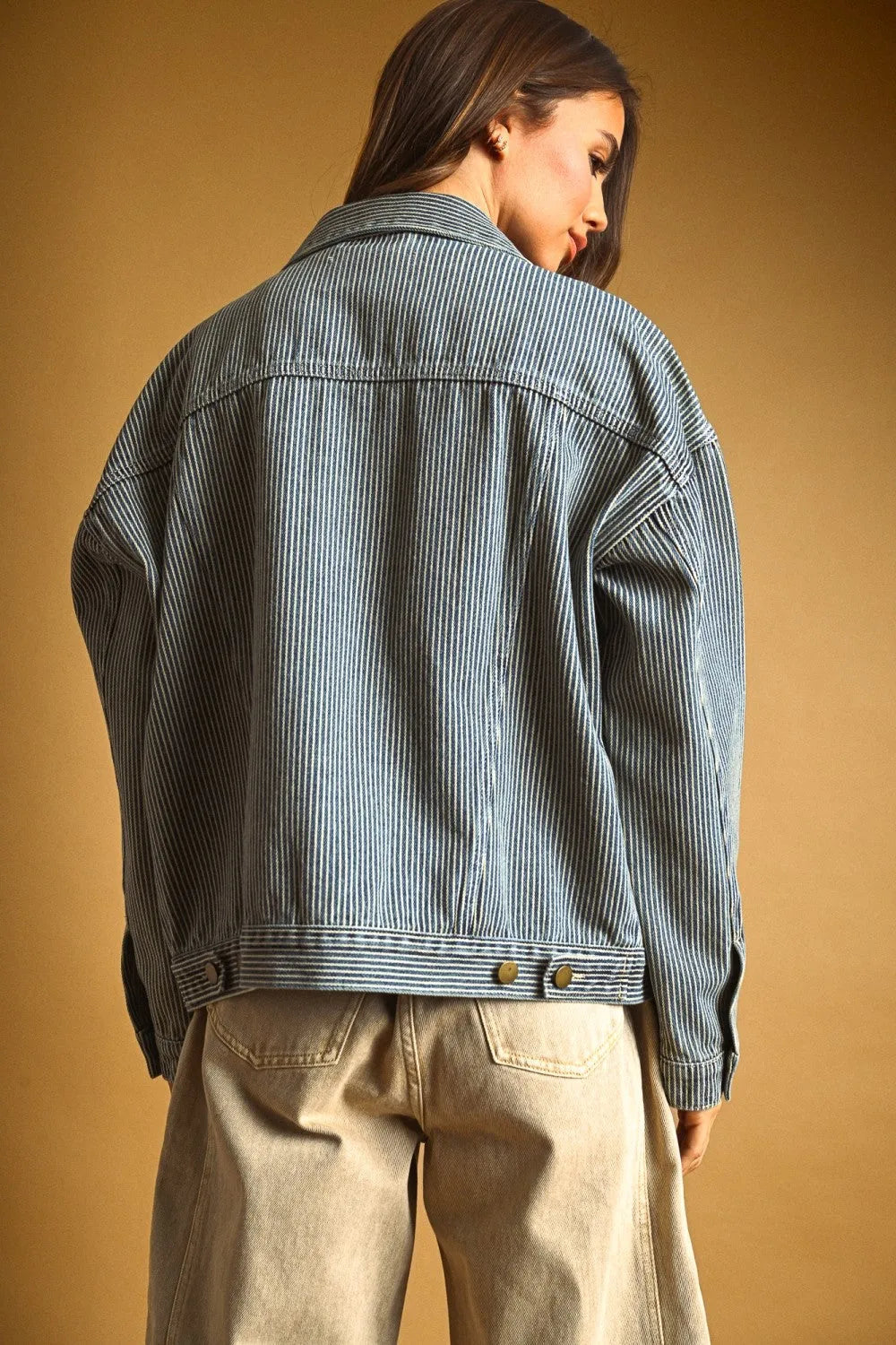 Striped pattern denim jacket in faded blue and white with vertical pinstripes and classic button closures at the waist