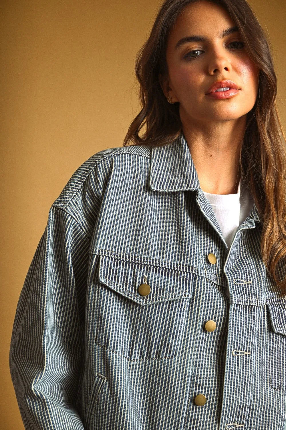 A striped pattern denim jacket in denim with vertical gray and white stripes and gold-tone buttons with classic collar