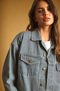 A striped pattern denim jacket in denim with vertical gray and white stripes and gold-tone buttons with classic collar