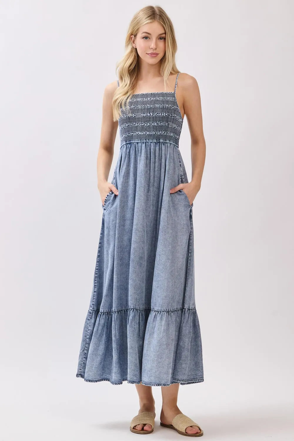A denim tiered midi dress featuring a tencel smocked patterned bodice and a flowing tiered skirt