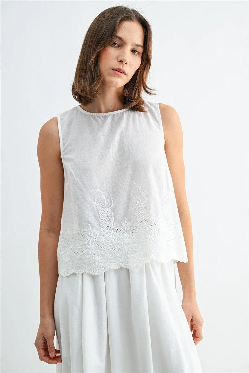 White sleeveless button blouse features eyelet hem with delicate lace embroidery along the back hem