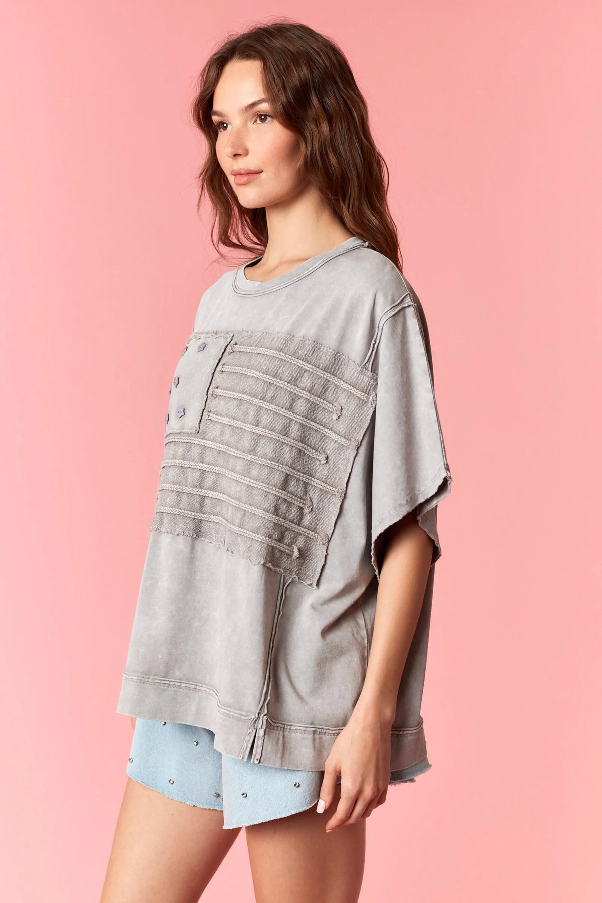 A faded gray oversized american flag garment t-shirt with patchwork horizontal panels and button details in garment dye wash