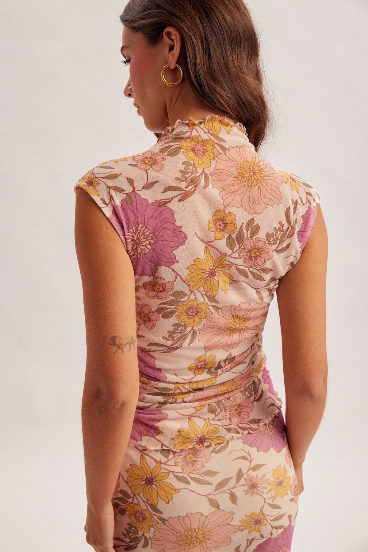 A fitted flora ruched sleeveless mesh top in soft beige with vibrant pink and yellow floral patterns