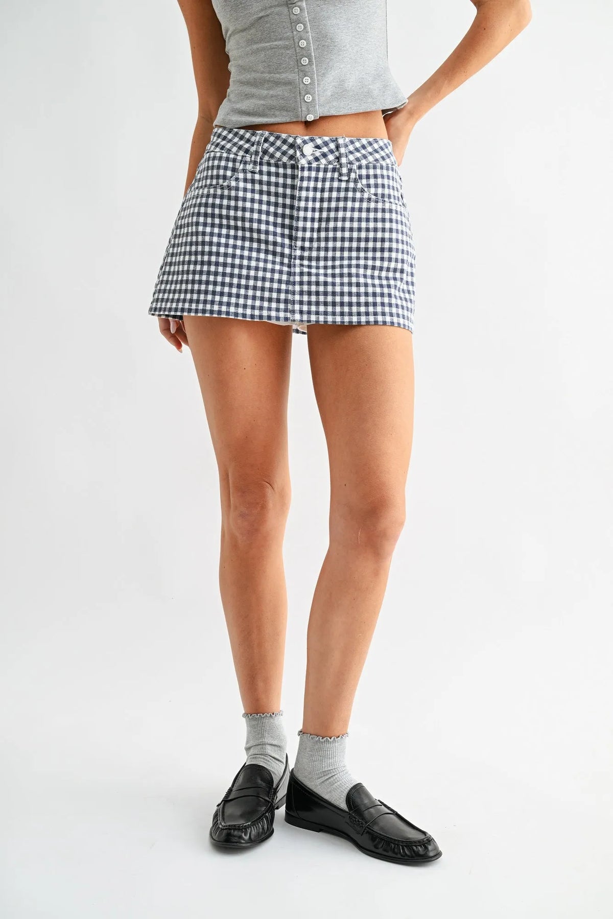 A fitted high-waisted gingham skort denim in black and white with button closures at the waist
