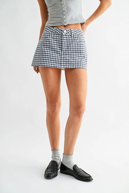 A fitted high-waisted gingham skort denim in black and white with button closures at the waist