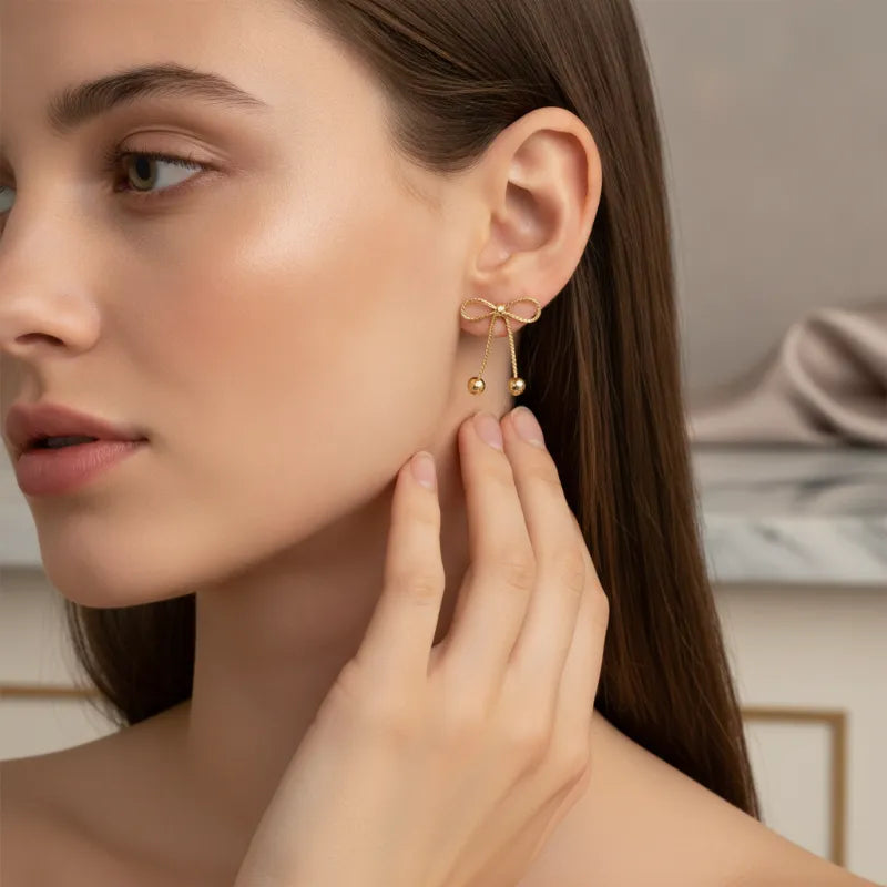 Dainty gold bow statement earrings featuring gold bow design with delicate sphere tassels for elegant wear