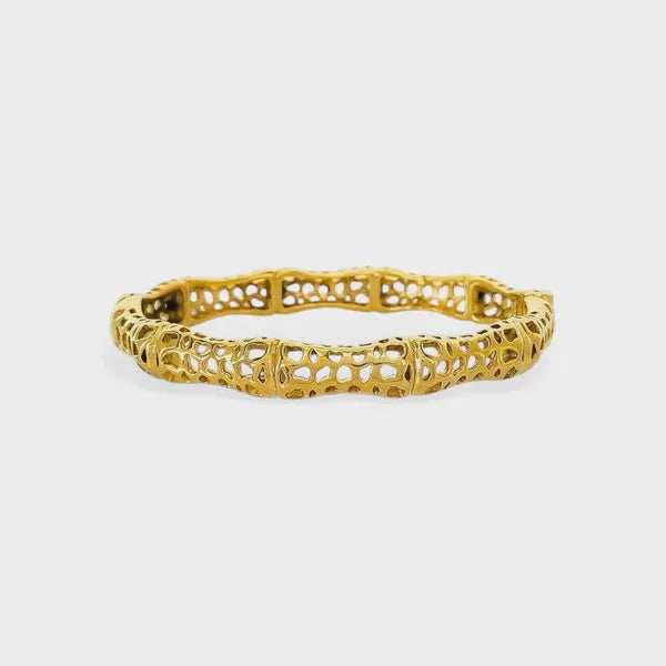 Gold-colored intricately designed sculptural lattice design bangle with delicate lace-like segmented structure