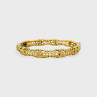 Gold-colored intricately designed sculptural lattice design bangle with delicate lace-like segmented structure