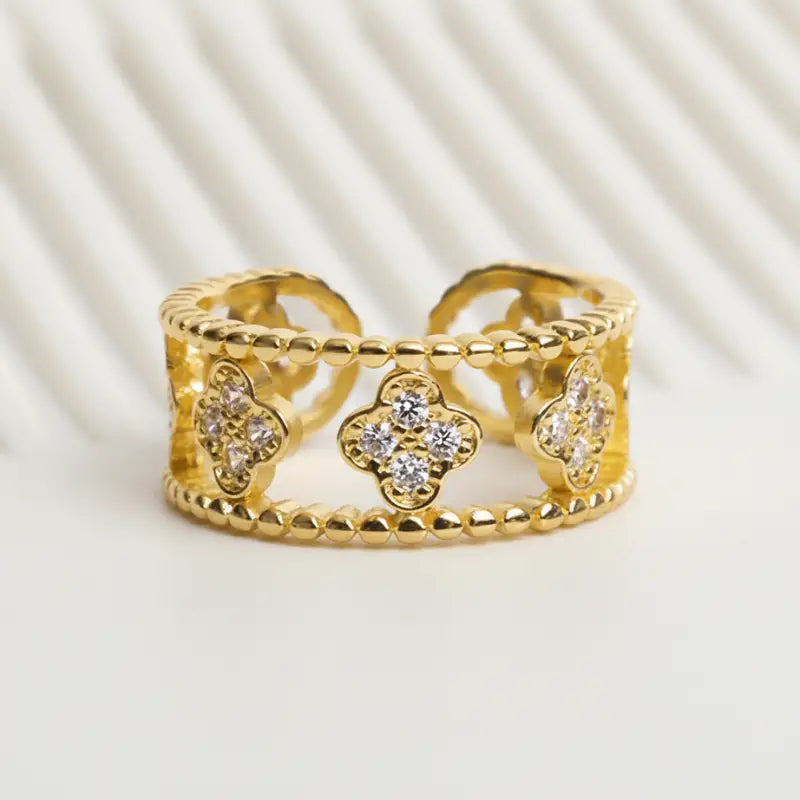 Gold-colored lucky clover cuff ring with beaded edge and three clover-shaped diamond clusters in gold