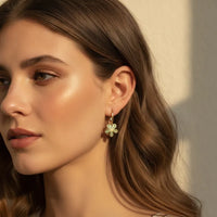 Gold rectangular hoops featuring a delicate four-leaf clover pendant with dainty sage green floral charms