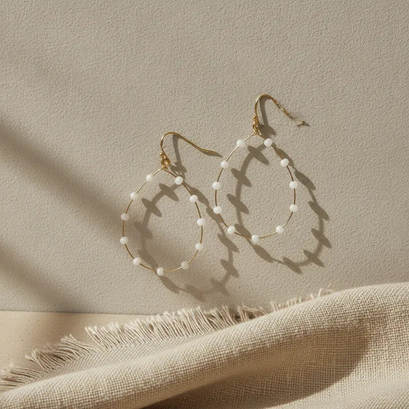 Dainty gold wire beaded teardrop earrings featuring gold hoops adorned with evenly spaced white beads