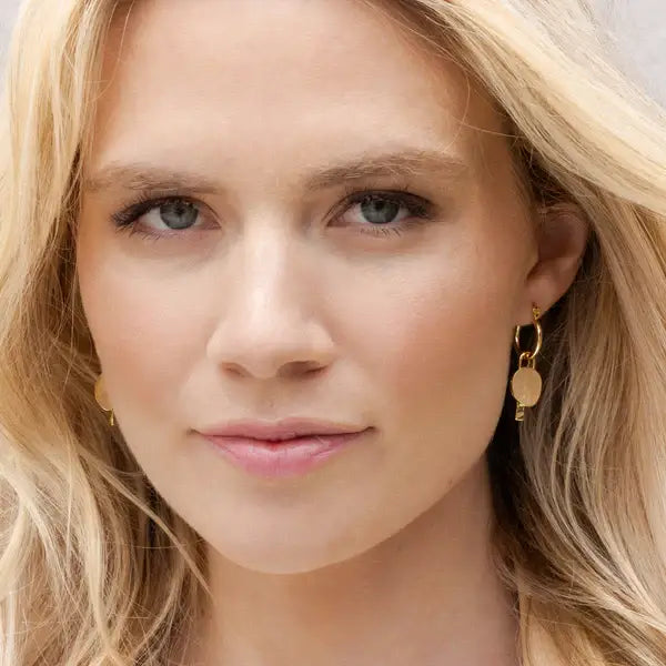 Gold hoop interchangeable charm earring with a dangling circular disc pendant in polished metal finish