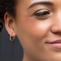 Gold hoop earring with a polished minimalist design as an interchangeable charm earring for versatile style
